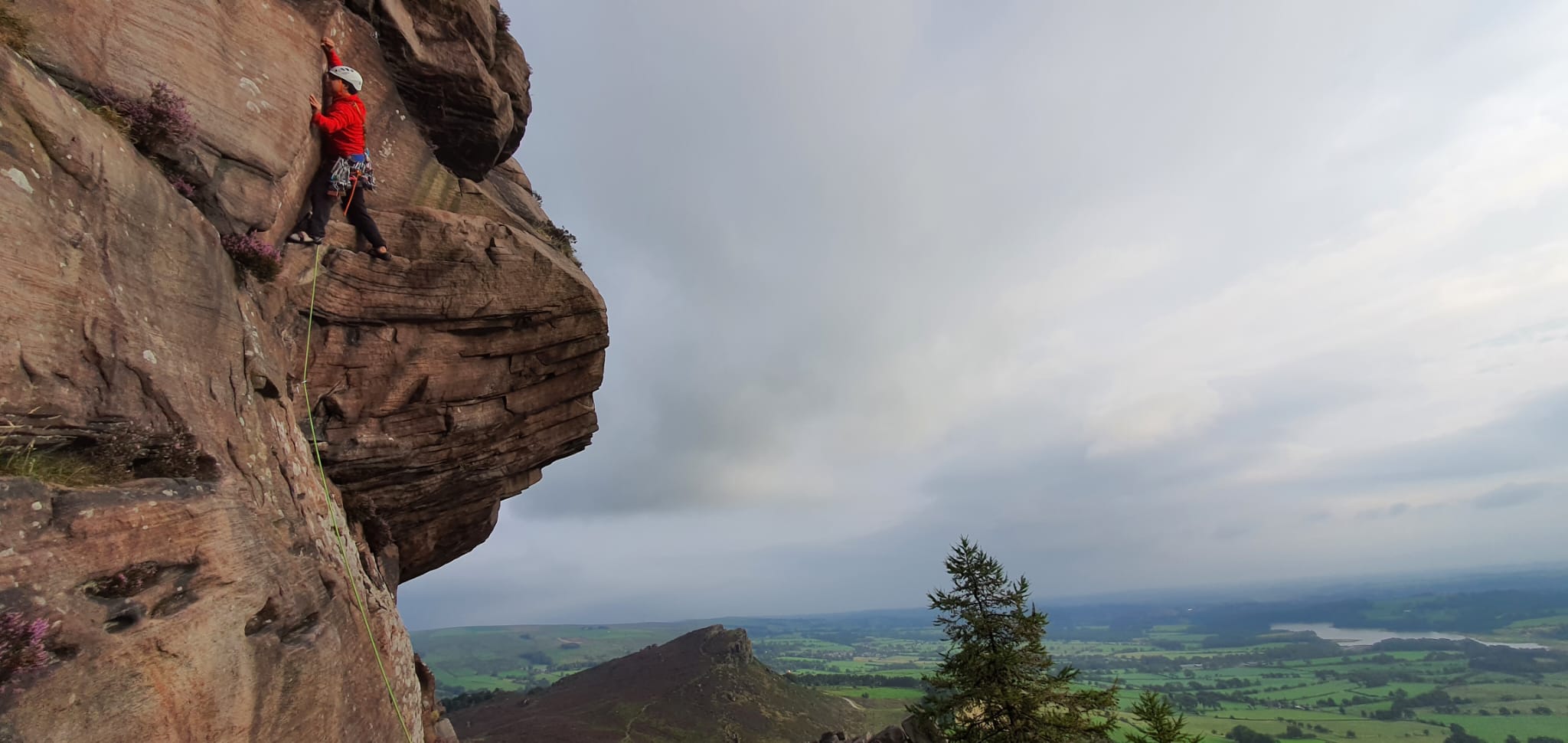 Professional climbing instructor ascending a sandstone rock face during an outdoor climbing session.